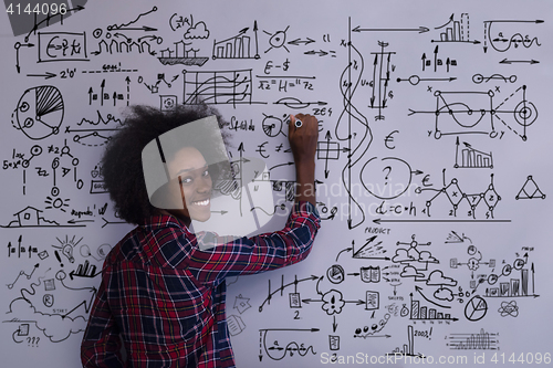 Image of African American woman writing on a chalkboard in a modern offic