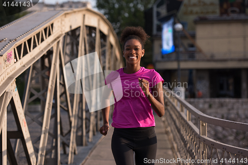 Image of african american woman running across the bridge