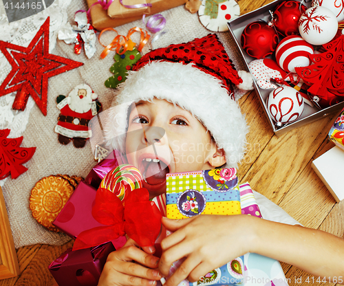 Image of little cute kid in santas red hat with handmade gifts, toys vint