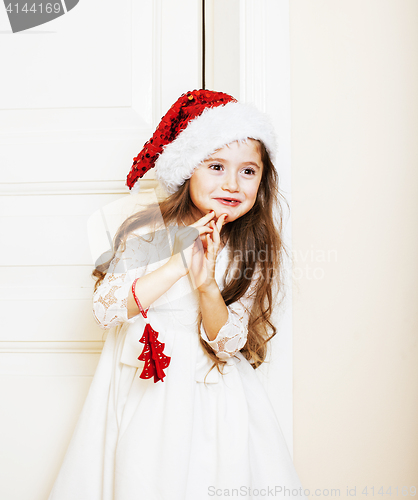 Image of little cute girl in santas red hat waiting for Christmas gifts. 