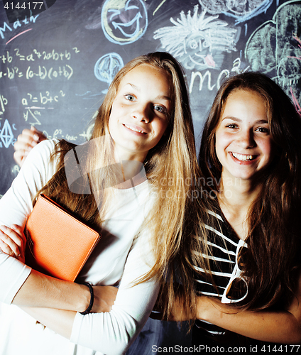 Image of back to school after summer vacations, two teen real girls in classroom with blackboard painted together