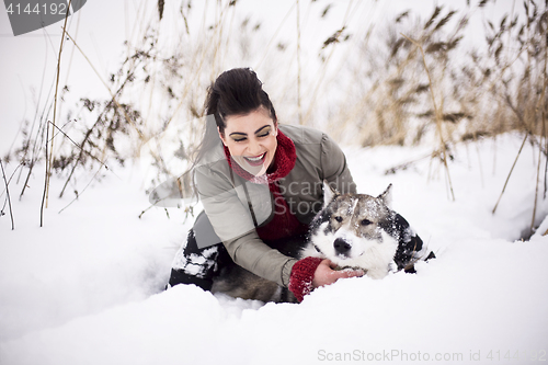 Image of Young fashion girl walking playing with husky dog outside in winter snow park, having fun together, lifestyle people concept