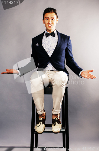 Image of young handsoman businessman fooling aroung with chair, wounderin