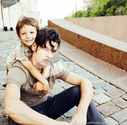 Image of little son with father in city hagging and smiling, casual look 