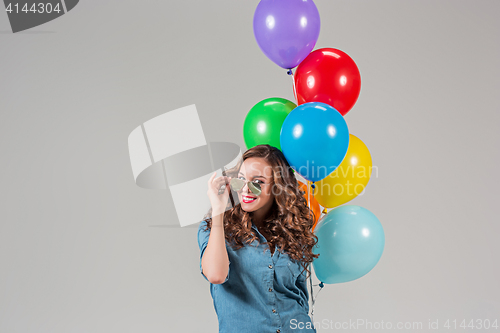Image of girl with sunglasses and bunch of colorful balloons