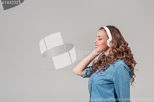 Image of Happy young woman listening music with headphones.