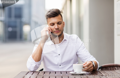 Image of man with coffee calling on smartphone at city cafe