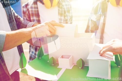 Image of close up of builders with paper house model