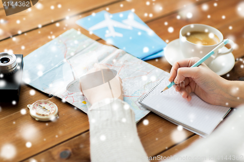 Image of hands with map and coffee writing to notebook