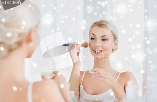 Image of woman with makeup brush and powder at bathroom