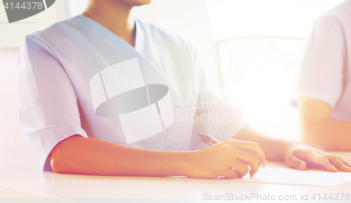 Image of close up of doctor taking notes at hospital