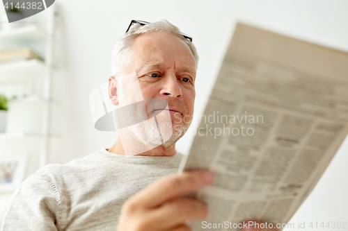 Image of close up of senior man reading newspaper at home