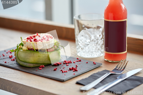 Image of salad, bottle of drink, glass and cutlery on table