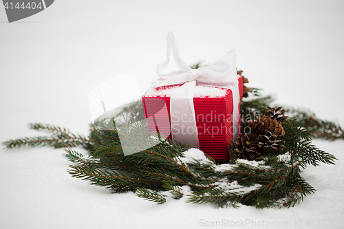 Image of christmas gift and fir wreath with cones on snow