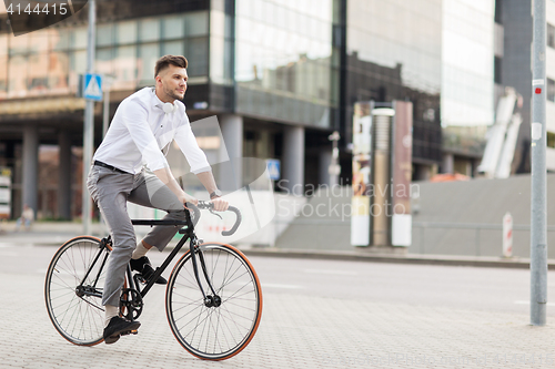 Image of man with headphones riding bicycle on city street