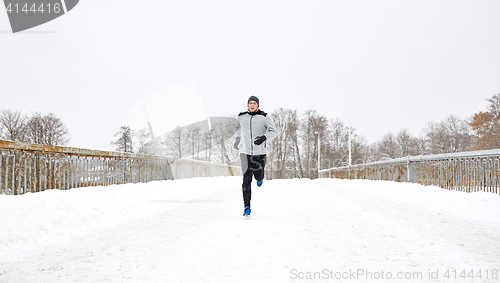 Image of man running along snow covered winter bridge road