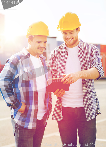 Image of smiling builders in hardhats with tablet pc