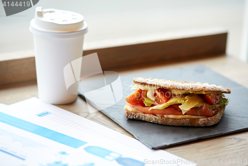 Image of salmon panini sandwich and cup of drink at cafe