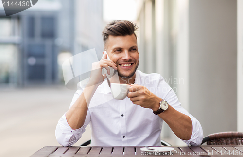 Image of man with coffee calling on smartphone at city cafe