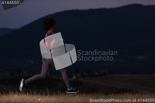 Image of Young African american woman jogging in nature