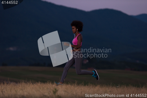 Image of Young African american woman jogging in nature