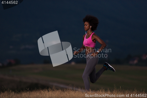 Image of Young African american woman jogging in nature