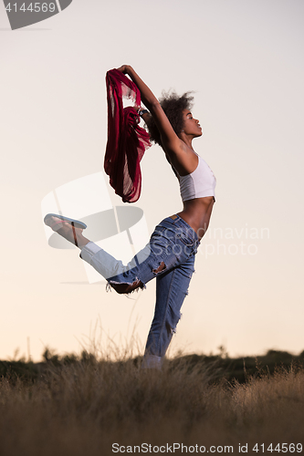 Image of black girl dances outdoors in a meadow