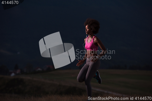 Image of Young African american woman jogging in nature