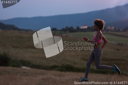 Image of Young African american woman jogging in nature