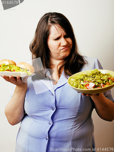 Image of fat white woman having choice between hamburger and salad close 