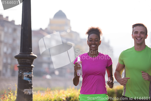 Image of young multiethnic couple jogging in the city