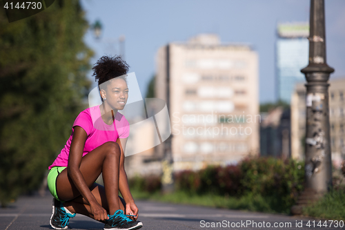 Image of African american woman runner tightening shoe lace