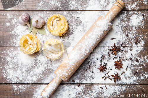 Image of Wooden rolling pin with flour and pasta