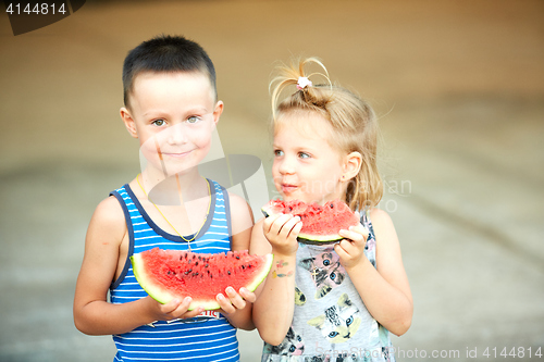 Image of Young girl and boy eating watermelon
