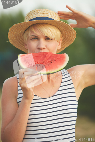 Image of Beautiful girl in straw hat eating fresh watermelon. Film camera style