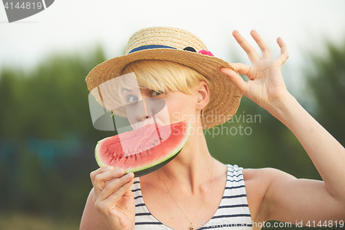 Image of Beautiful girl in straw hat eating fresh watermelon. Film camera style