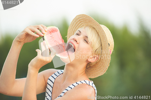 Image of Beautiful girl in straw hat eating fresh watermelon. Film camera style