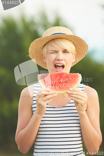 Image of Beautiful girl in straw hat eating fresh watermelon. Film camera style