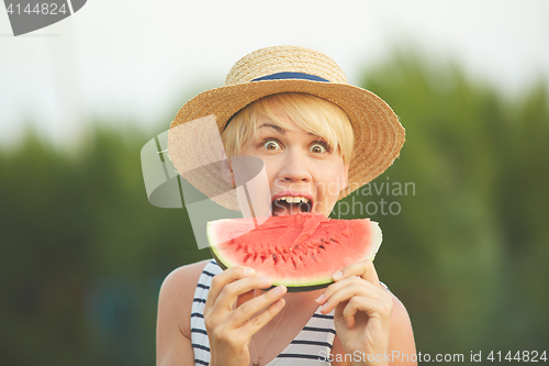 Image of Beautiful girl in straw hat eating fresh watermelon. Film camera style