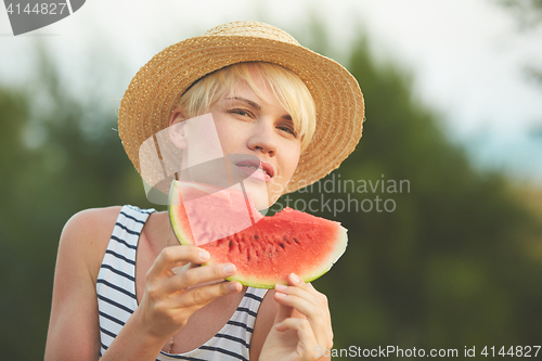 Image of Beautiful girl in straw hat eating fresh watermelon. Film camera style