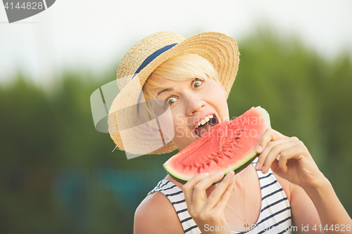 Image of Beautiful girl in straw hat eating fresh watermelon. Film camera style