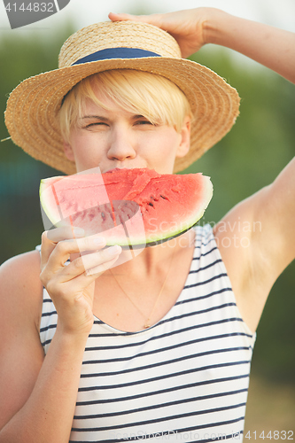 Image of Beautiful girl in straw hat eating fresh watermelon. Film camera style