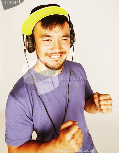 Image of young asian man in hat and headphones listening music on white b