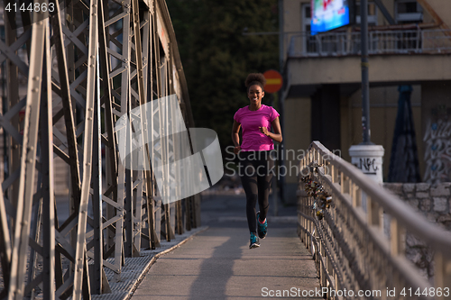 Image of african american woman running across the bridge