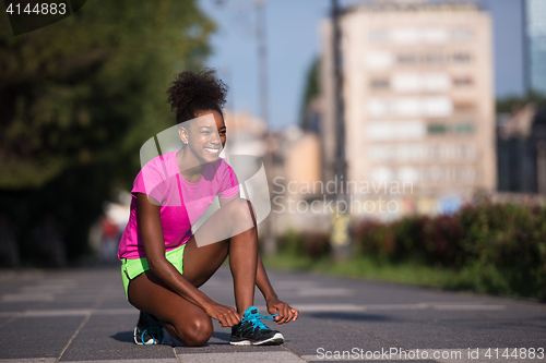 Image of African american woman runner tightening shoe lace