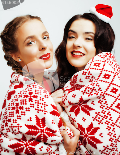 Image of young pretty happy smiling blond and brunette woman girlfriends on christmas in santas red hat and holiday decorated plaid, lifestyle people concept