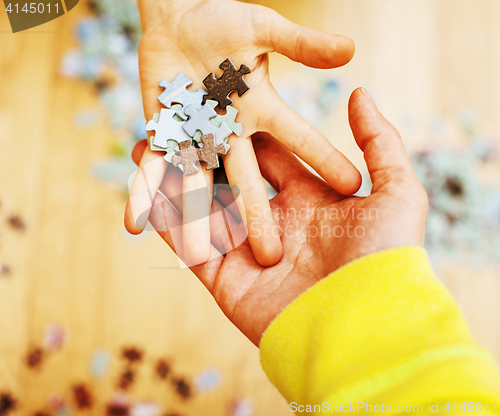 Image of little kid playing with puzzles on wooden floor together with pa