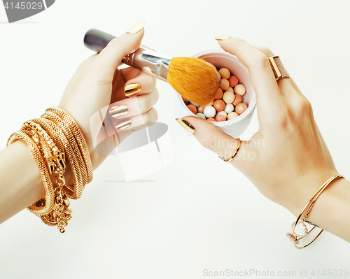 Image of woman hands with golden manicure and many rings holding brushes,
