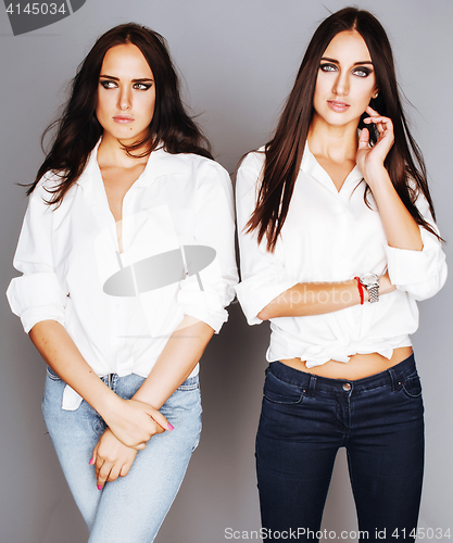 Image of two sisters twins posing, making photo selfie, dressed same whit