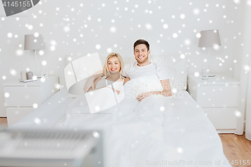 Image of happy couple lying in bed at home and watching tv